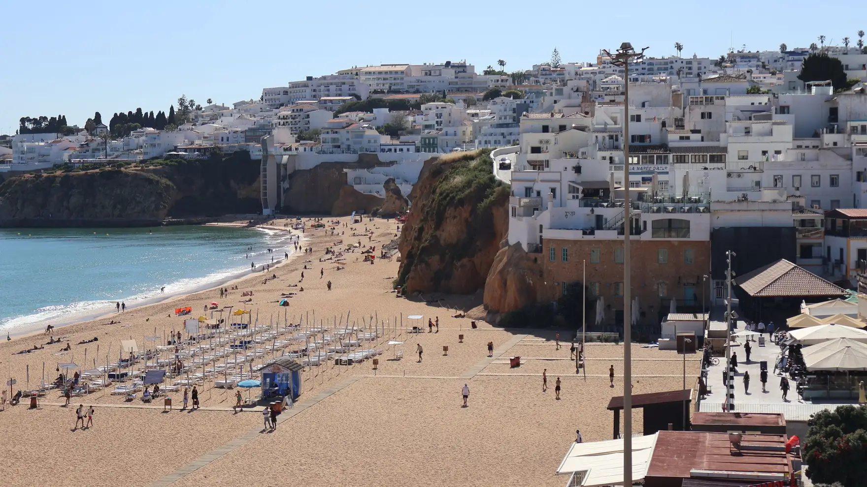 Charming beachfront scene with cascading white-washed buildings and golden sands in Albufeira, Portugal
