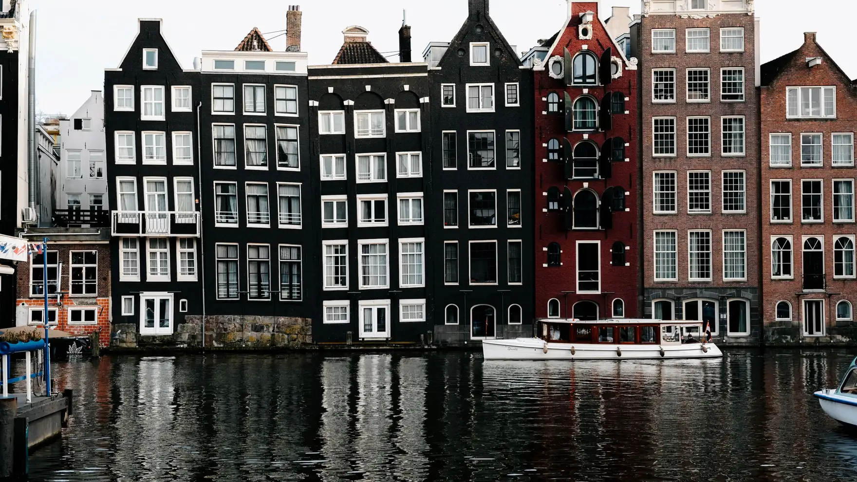 Stunning view of Amsterdam's iconic canal houses reflecting on water, showcasing unique architecture