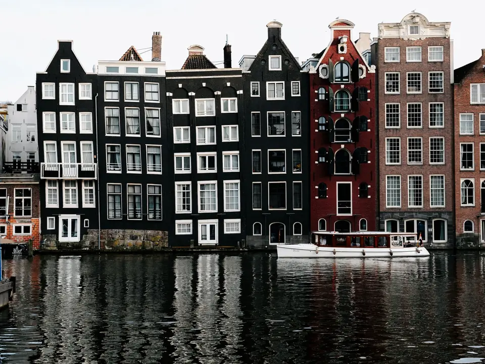 Stunning view of Amsterdam's iconic canal houses reflecting on water, showcasing unique architecture