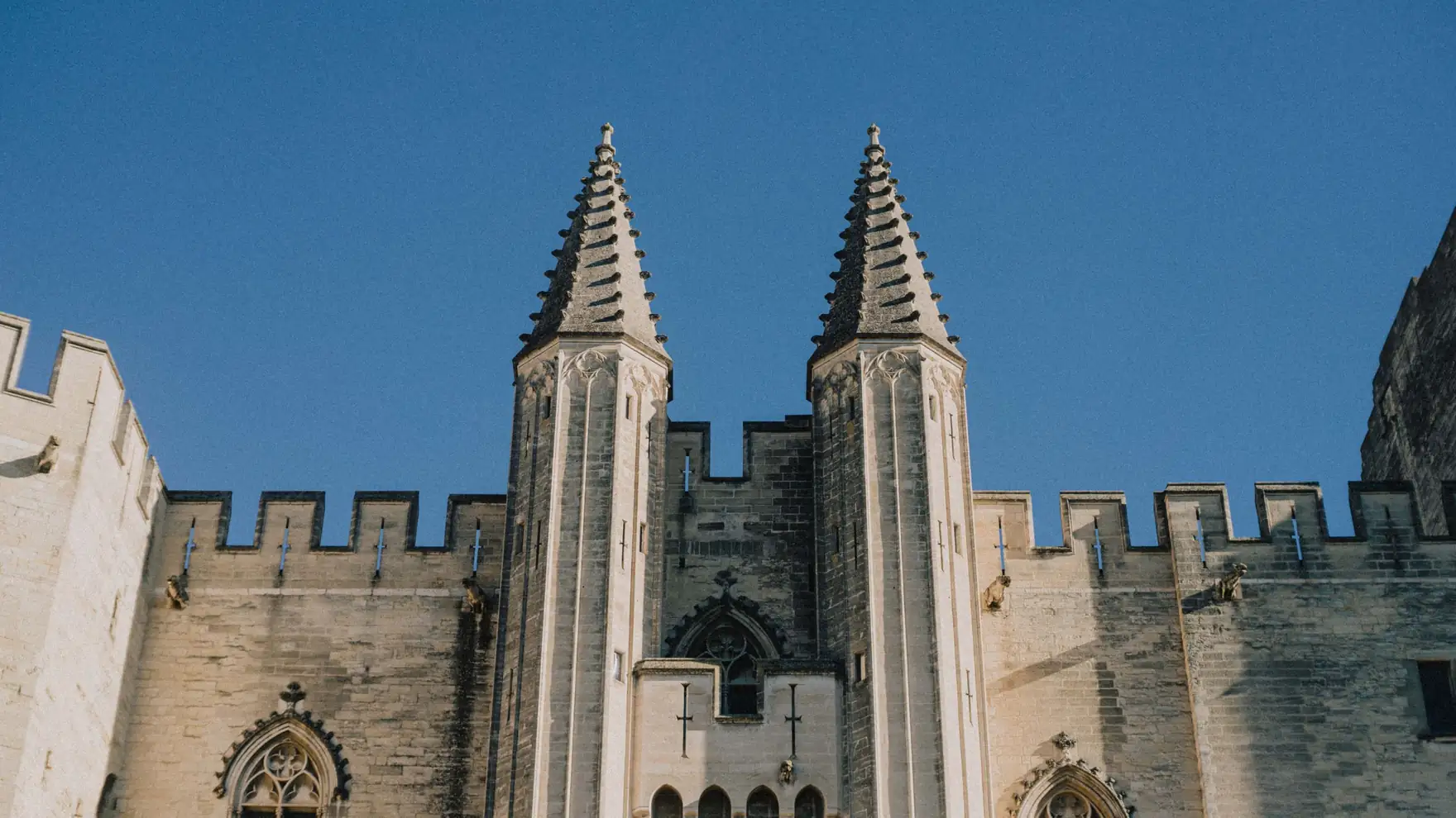 Majestic view of the Papal Palace towers under a clear blue sky in Avignon, France