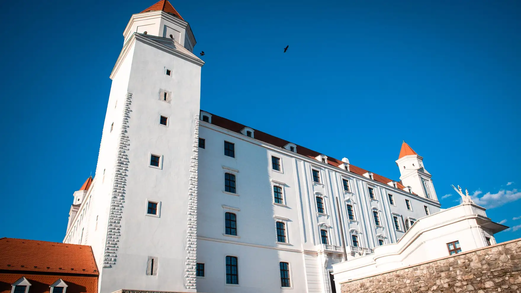 A breathtaking view of Bratislava Castle with its white towers and red roofs under a clear blue sky