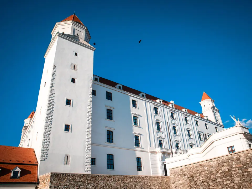 A breathtaking view of Bratislava Castle with its white towers and red roofs under a clear blue sky