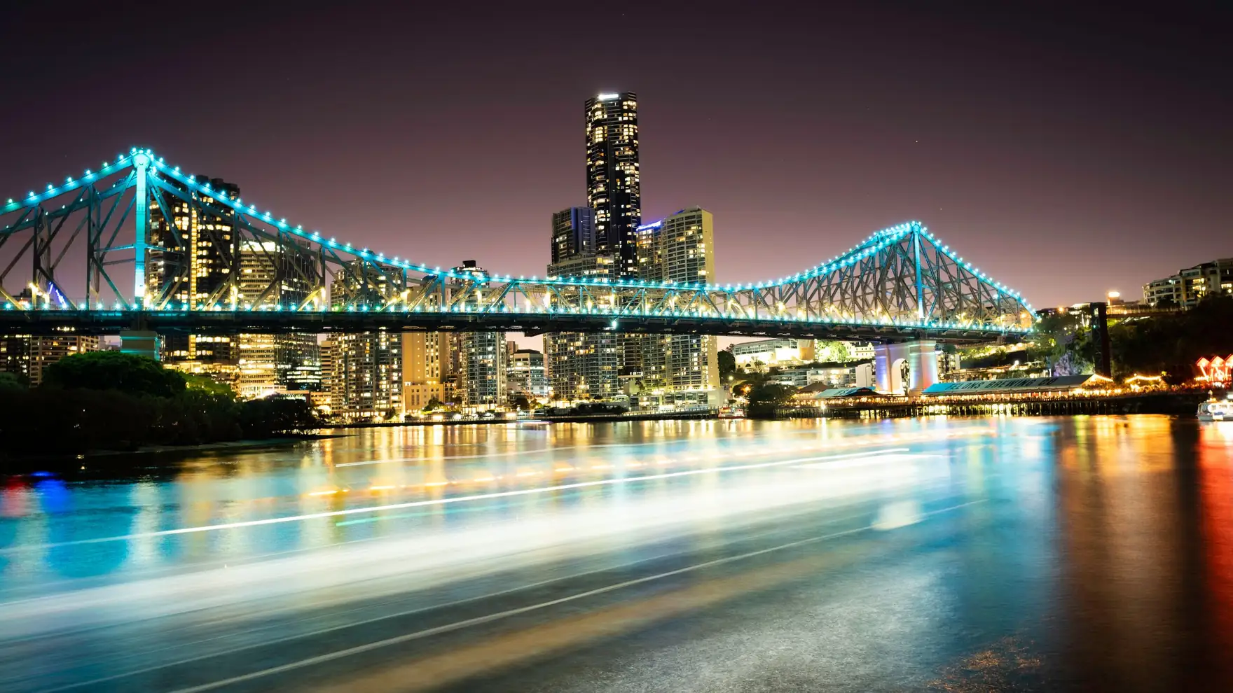 Bright cityscape view of Story Bridge in Brisbane at night with vibrant reflections on the river