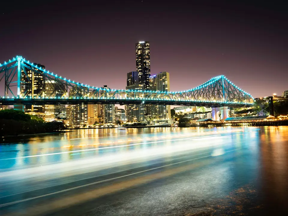 Bright cityscape view of Story Bridge in Brisbane at night with vibrant reflections on the river
