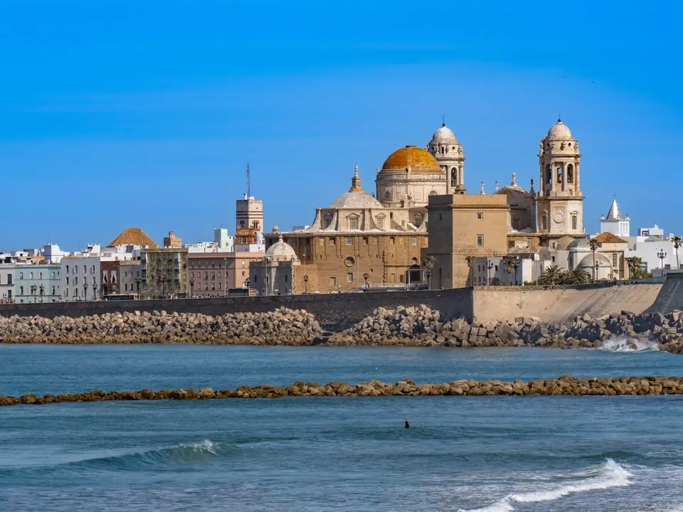 Scenic view of Cádiz Cathedral and waterfront, capturing iconic Andalusian architecture against a clear blue sky