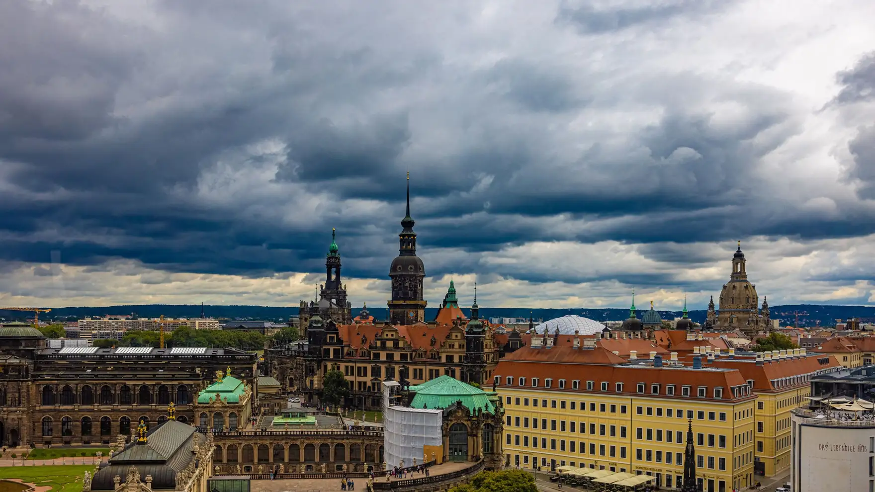 View of Dresden's historic architecture under dramatic cloudy skies. Features famous landmarks