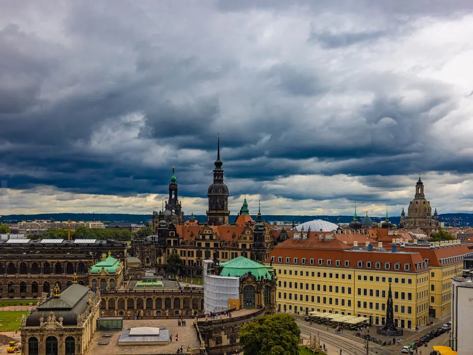 View of Dresden's historic architecture under dramatic cloudy skies. Features famous landmarks