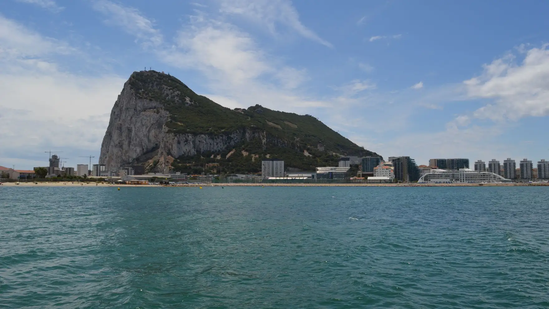 Beautiful view of the Rock of Gibraltar and waterfront buildings under a blue sky
