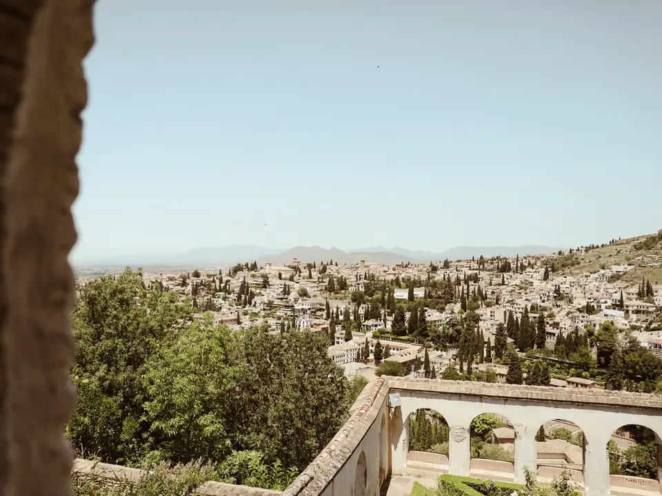 Panoramic view of Granada cityscape framed by historic architecture under a summer sky