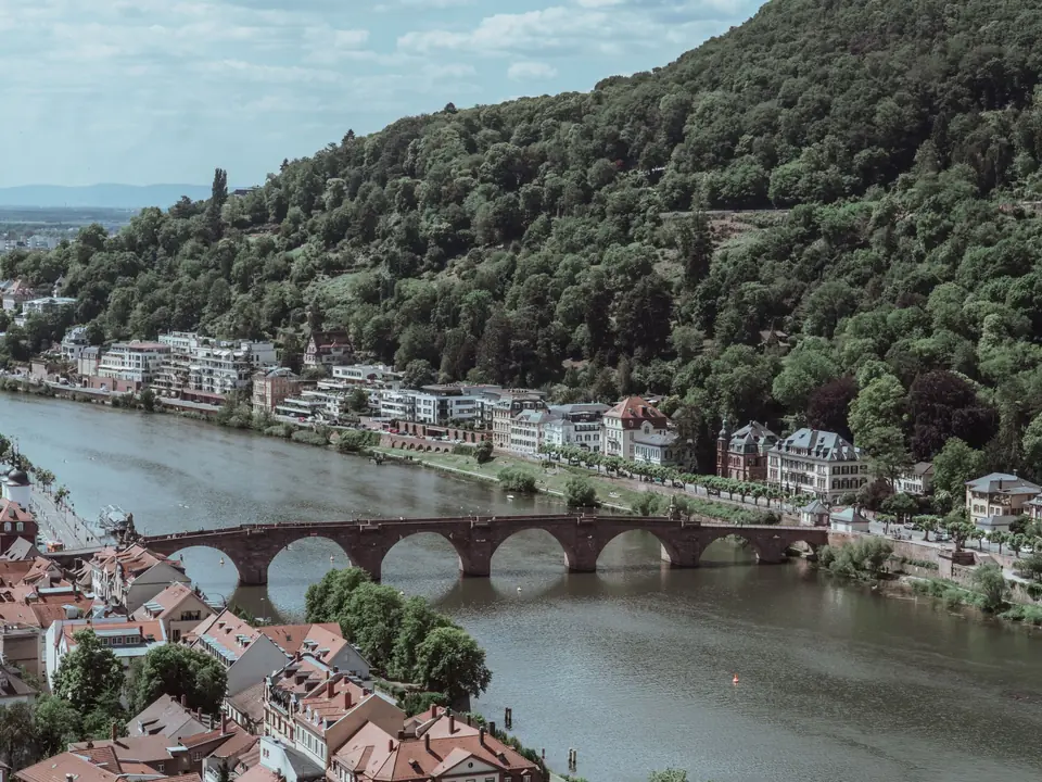 Scenic aerial view of Heidelberg, showcasing its historic bridge over the Neckar River surrounded by lush hills