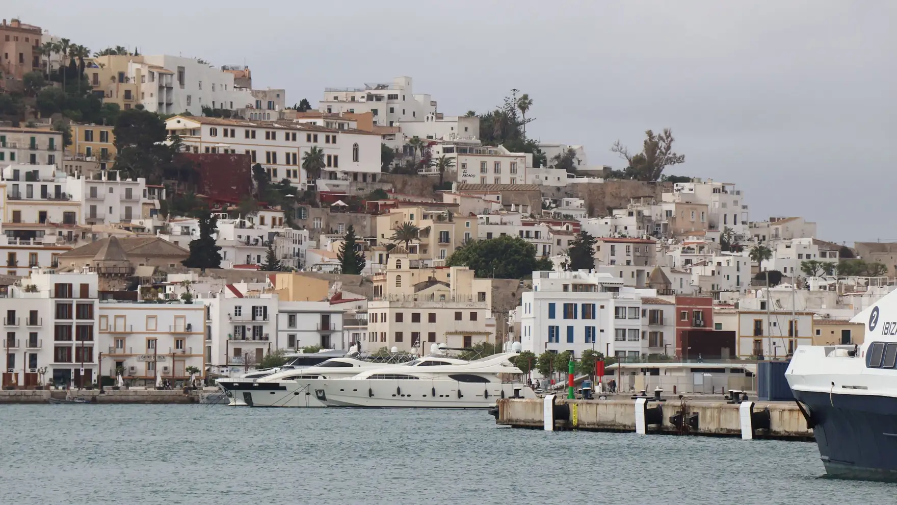 Panoramic view of Ibiza's old town architecture and luxury yachts in the marina, Balearic Islands