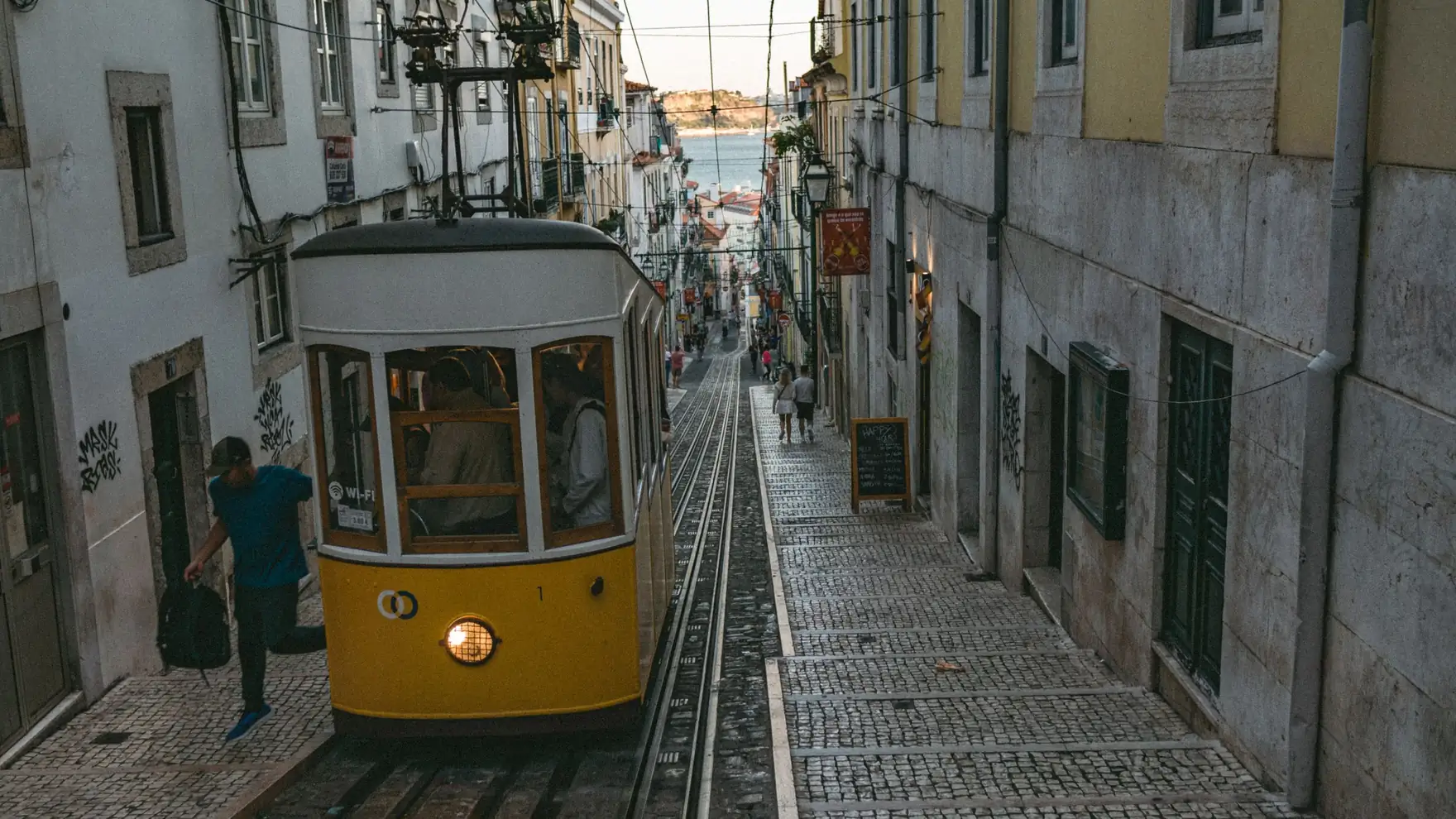 Vintage tram navigates a quaint cobblestone street in Lisbon, Portugal, capturing urban charm