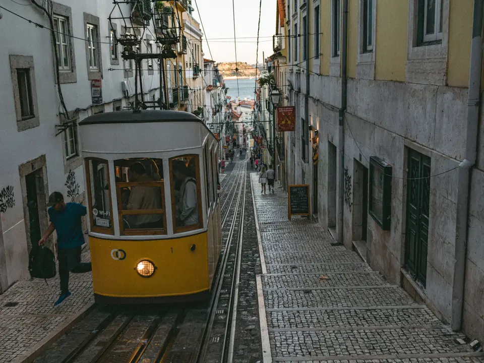 Vintage tram navigates a quaint cobblestone street in Lisbon, Portugal, capturing urban charm