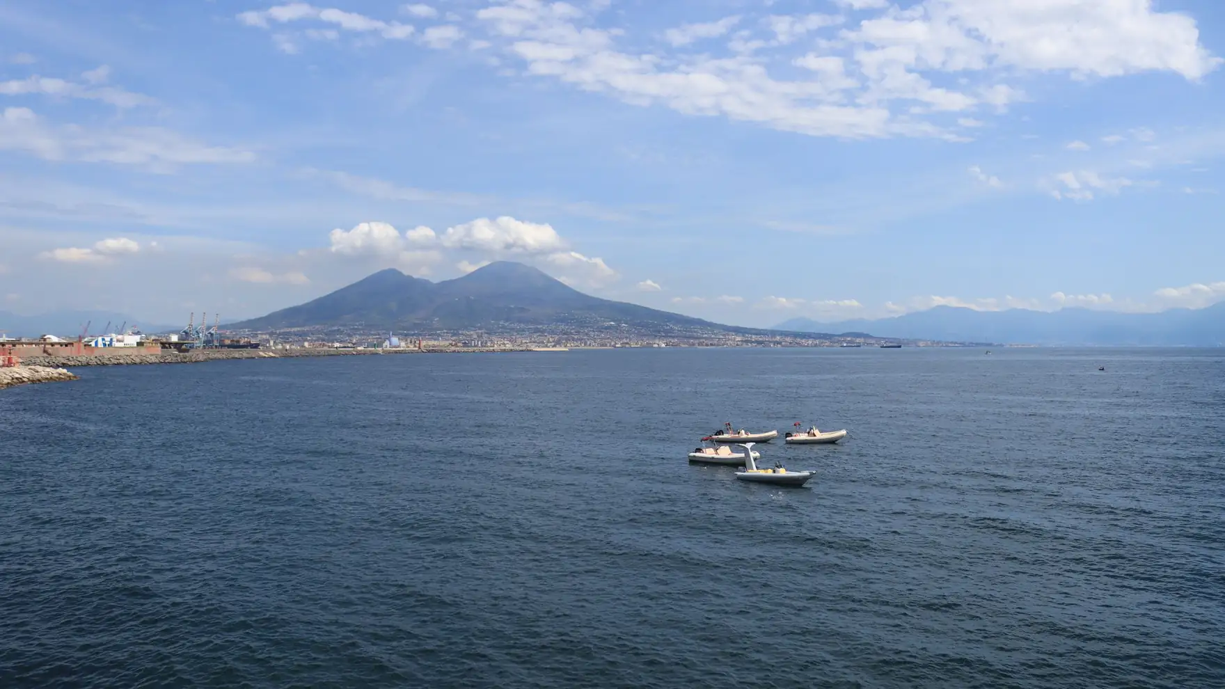 A stunning aerial view of Mount Vesuvius with boats sailing through the picturesque Bay of Naples