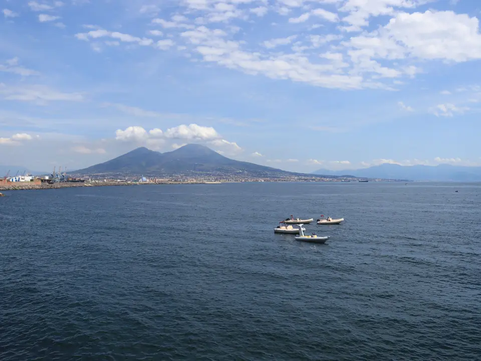 A stunning aerial view of Mount Vesuvius with boats sailing through the picturesque Bay of Naples
