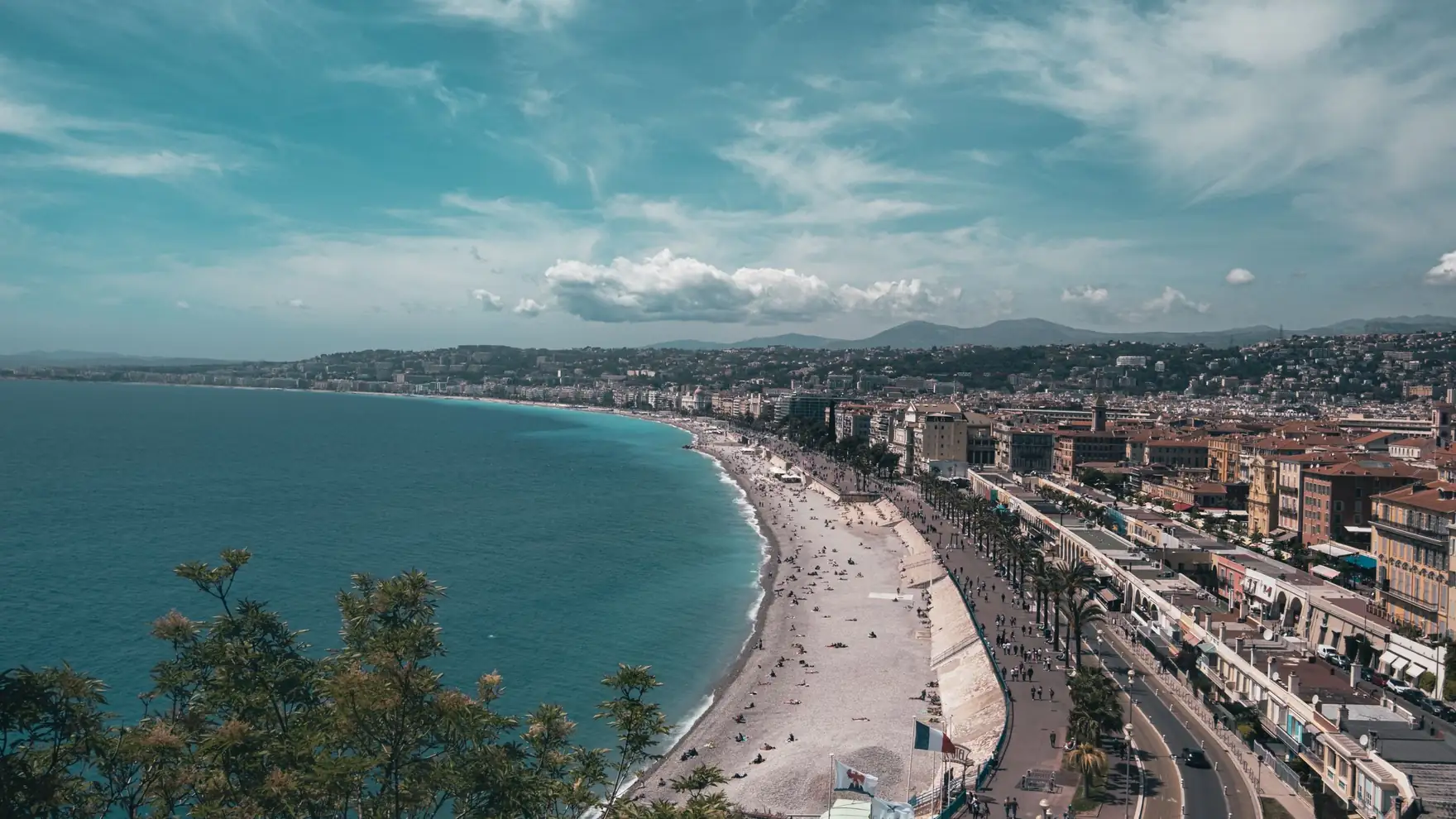 Stunning aerial view of Nice, France with bustling beachfront under a clear summer sky