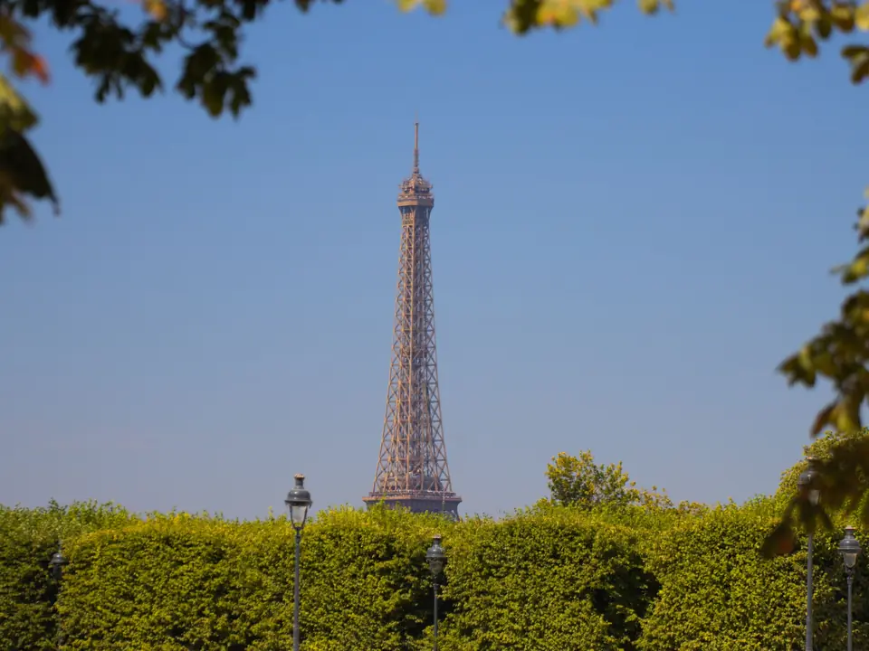 Scenic view of the Eiffel Tower framed by lush green trees against a clear blue sky in Paris, France