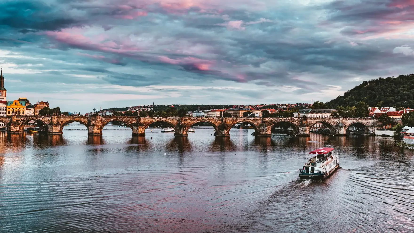 Stunning view of Charles Bridge with vibrant sunset hues over Vltava River in Prague
