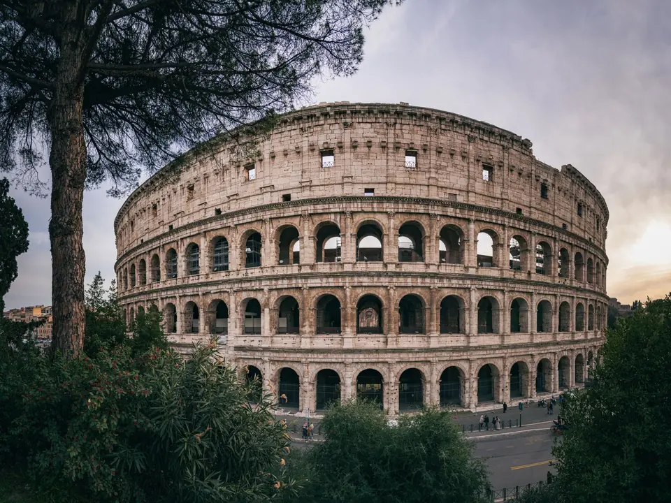 Captivating wide-angle shot of Rome's iconic Colosseum with a serene sunset backdrop