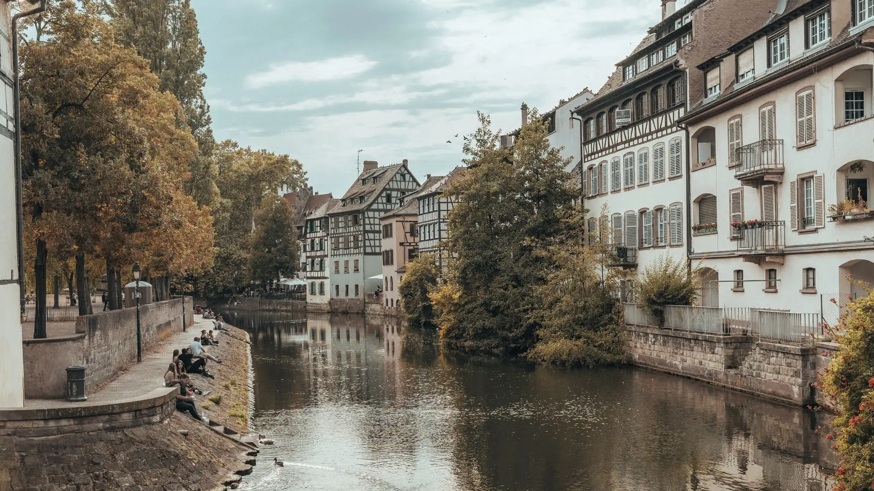 Scenic view of Strasbourg's historic canal lined with quaint buildings and autumn trees