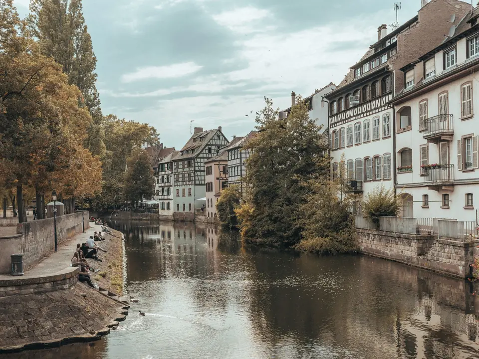 Scenic view of Strasbourg's historic canal lined with quaint buildings and autumn trees