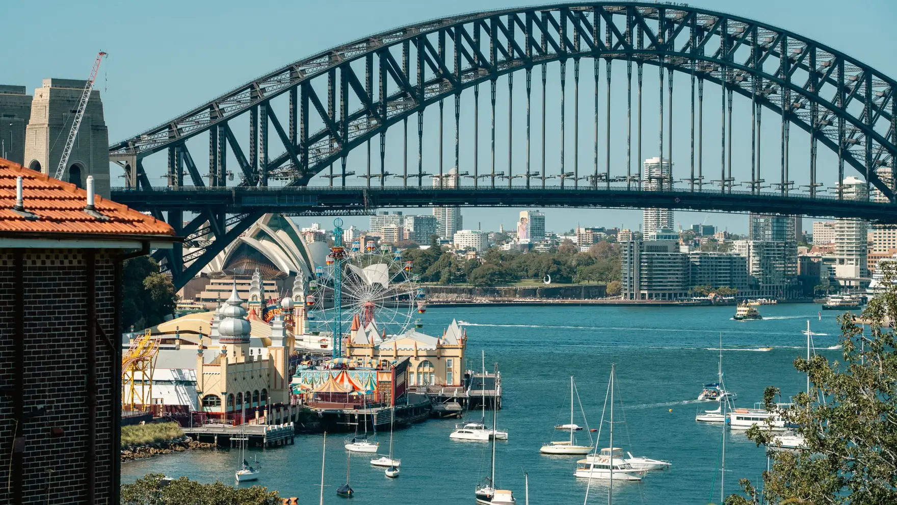 A vibrant view of Sydney Harbour Bridge with Luna Park and sailboats highlighting the iconic skyline